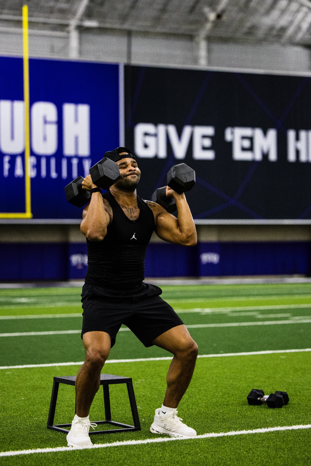 Athlete pressing dumbbells overhead during a workout